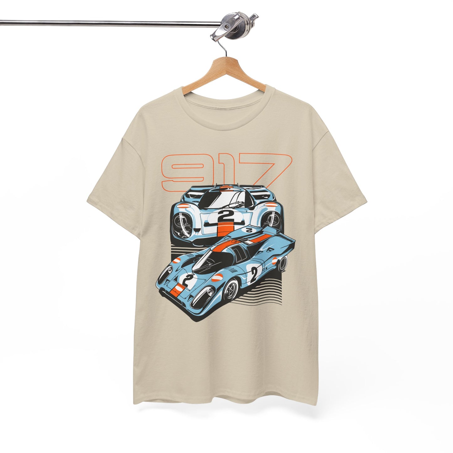 Beige t-shirt elegantly displayed on a hanger, showcasing a luxurious graphic design of two Porsche 917 cars with vivid orange detailing.