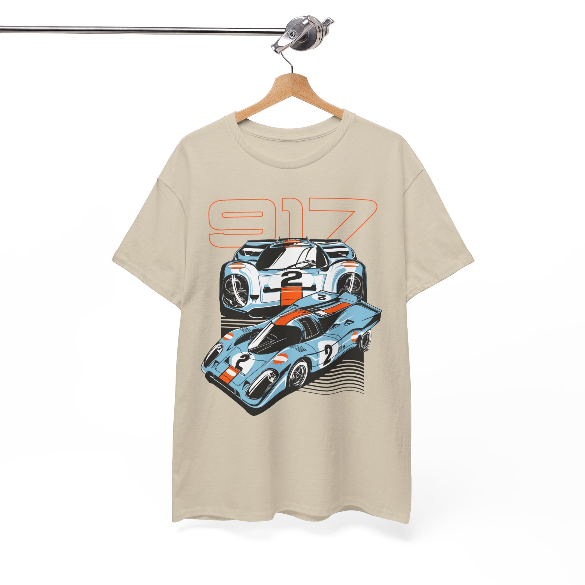 Beige t-shirt elegantly displayed on a hanger, showcasing a luxurious graphic design of two Porsche 917 cars with vivid orange detailing.