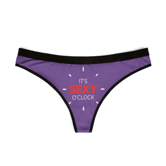 Stylish women's thong in vibrant purple showcasing the fun phrase 'It's Sexy O'Clock' in striking red, perfect for adding a touch of humour to intimate apparel.