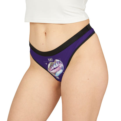 Elegant purple thong worn by a model, displaying a chic design with iridescent lips and shimmering text, exuding playful sensuality.