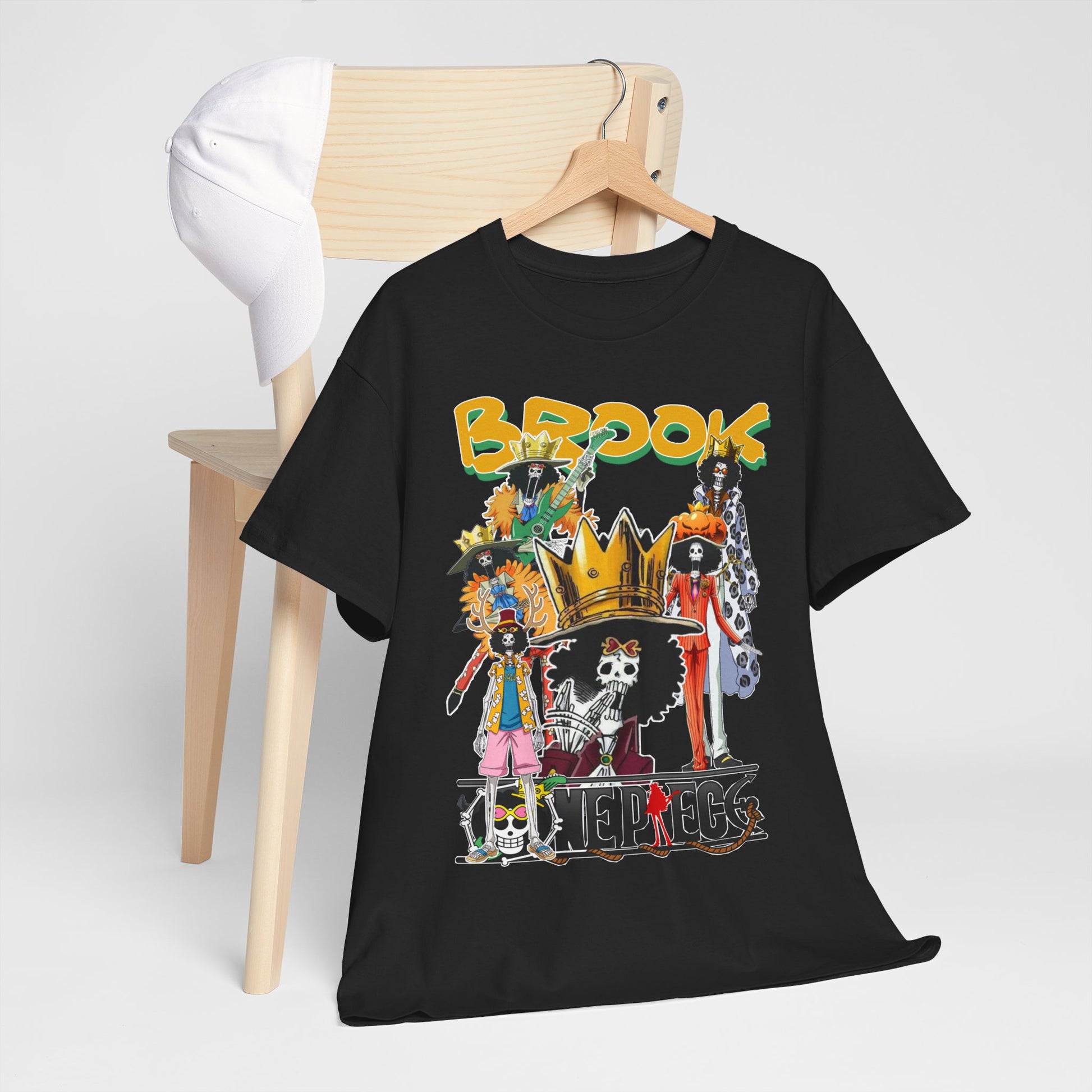 Sophisticated black anime t-shirt displayed on a stylish wooden chair next to a white cap, featuring an eye-catching collage of Brook characters, perfect for casual wear.