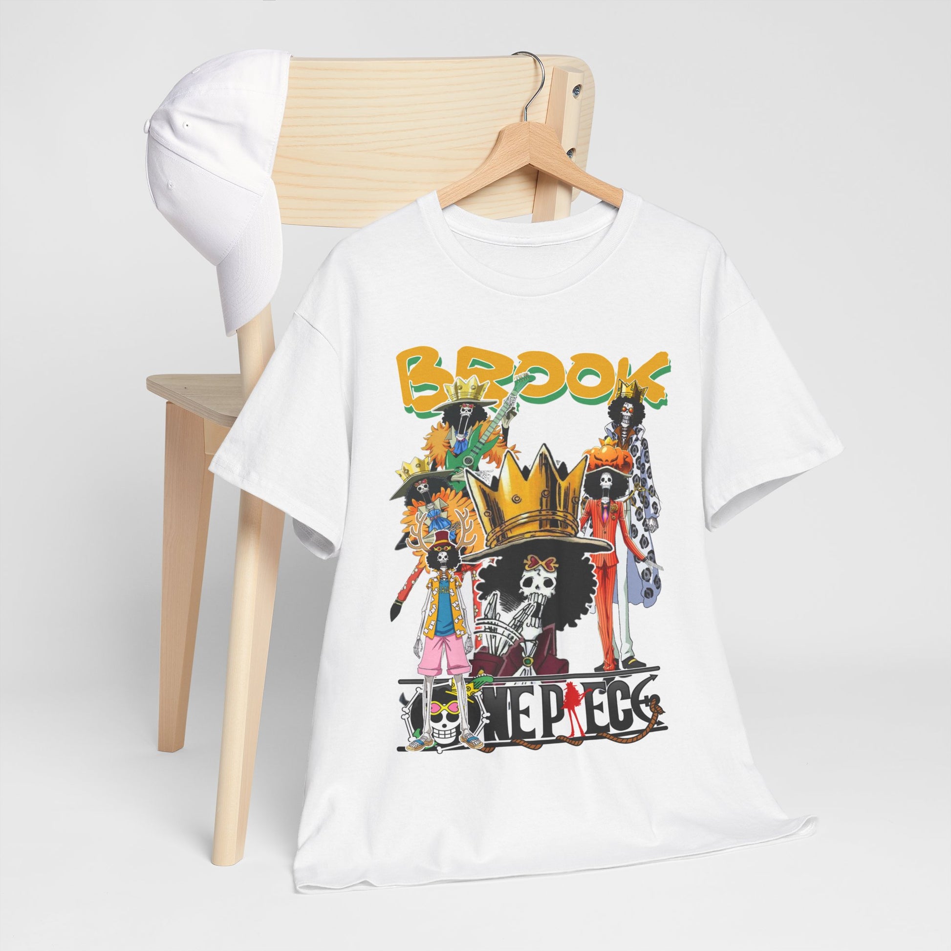 Chic white t-shirt showcasing a colourful Brook characters collage from anime, artistically arranged next to a stylish cap on a wooden chair for a trendy look.