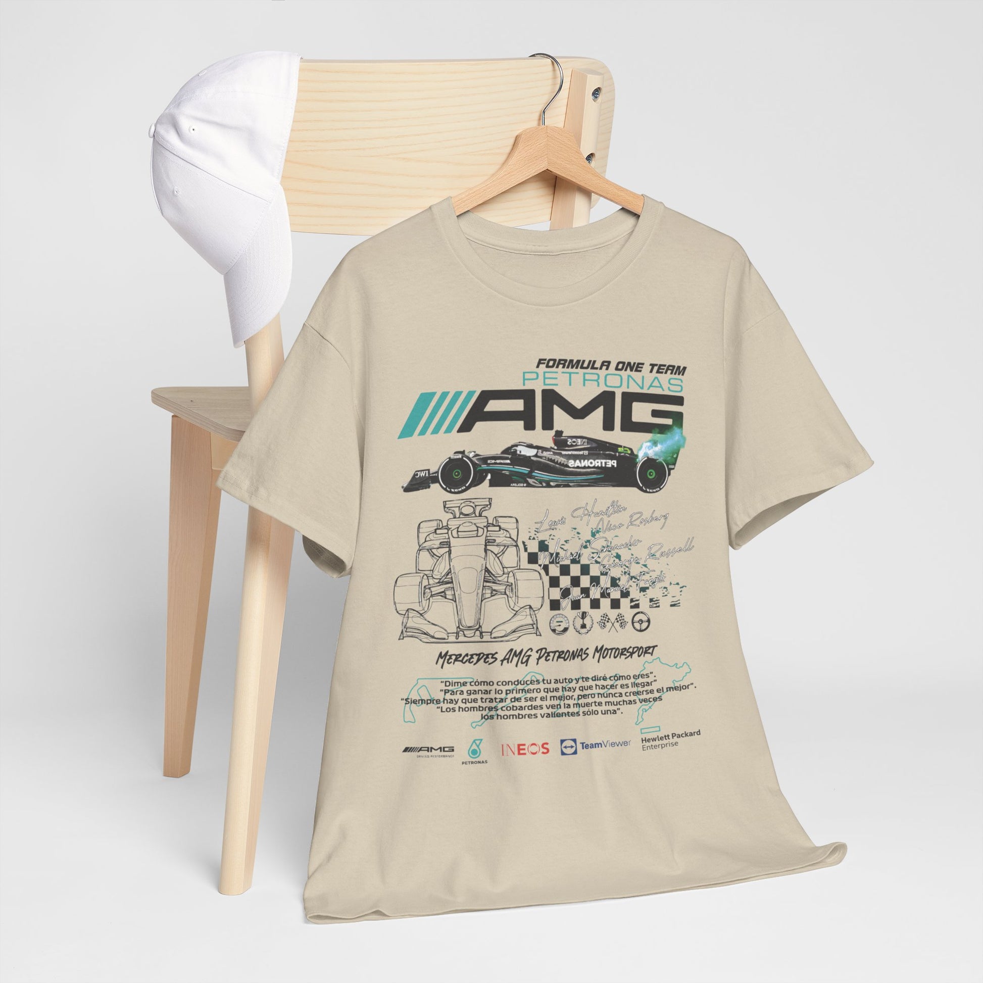 Stylish F1 Mercedes AMG Petronas T-Shirt displayed on a chair alongside a white cap, featuring intricate race car artwork and elegant typography.