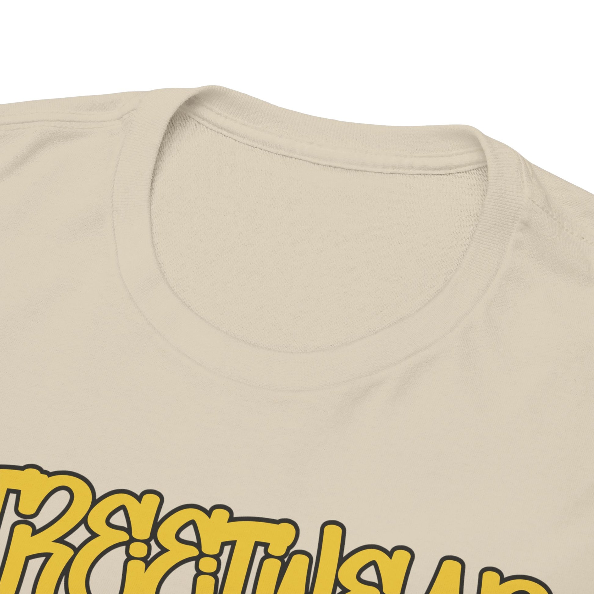 Close-up view of the neckline and intricate design details of a luxurious beige t-shirt, featuring striking yellow text and unique artwork.