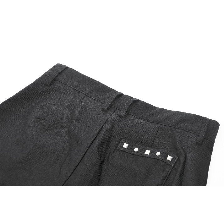 Close-up of dark pleated garter shorts showcasing intricate silver grommet embellishments, highlighting the edgy luxury of alternative fashion.