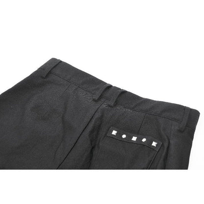 Close-up of dark pleated garter shorts showcasing intricate silver grommet embellishments, highlighting the edgy luxury of alternative fashion.