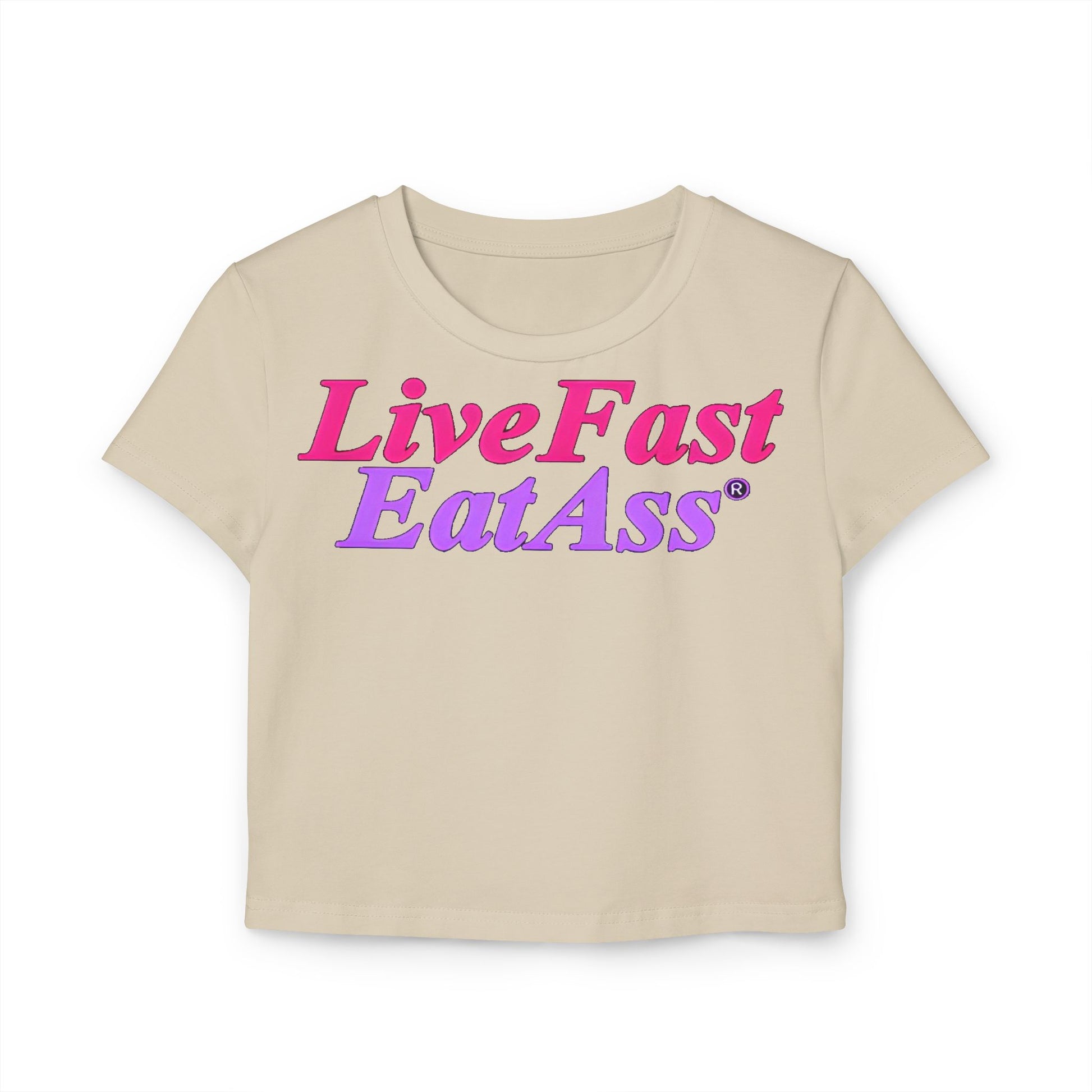 Front view of a cream cropped t-shirt displaying the eye-catching phrase 'Live Fast EatAss' in hot pink and purple, a perfect blend of luxury and fun.