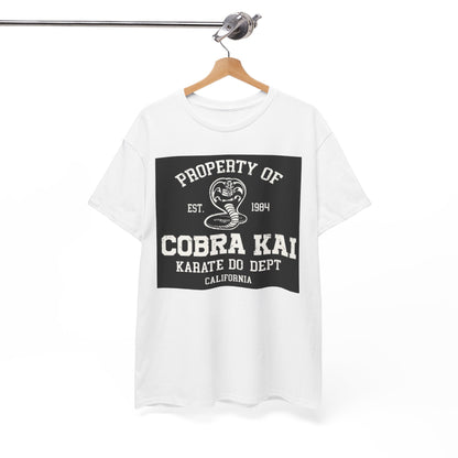 A sophisticated white graphic t-shirt featuring the Cobra Kai emblem, artistically displayed on a wooden hanger, reflecting a blend of style and athleticism.