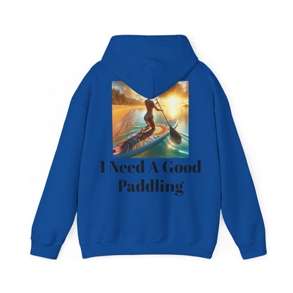 Fantasy Paddleboarding Unisex Hooded Sweatshirt in blue, adorned with a vibrant image of a woman paddling at sunset, complemented by the playful slogan 'I Need A Good Paddling'.