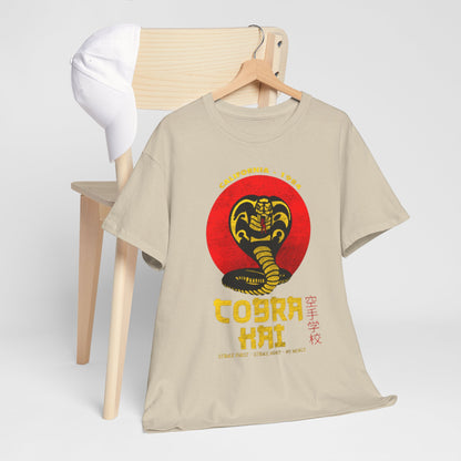 Sophisticated beige Cobra Kai T-shirt artfully arranged on a chair with a cap. Showcases the iconic cobra motif, ideal for adding a touch of pop culture flair to any casual look.