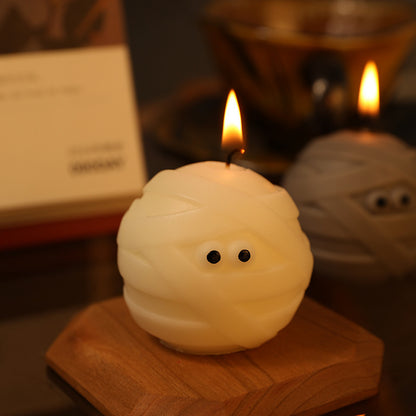 Elegant Halloween Scented Candle Set displaying a lit white mummy candle on a chic wooden base, creating a luxurious atmosphere for Halloween celebrations.