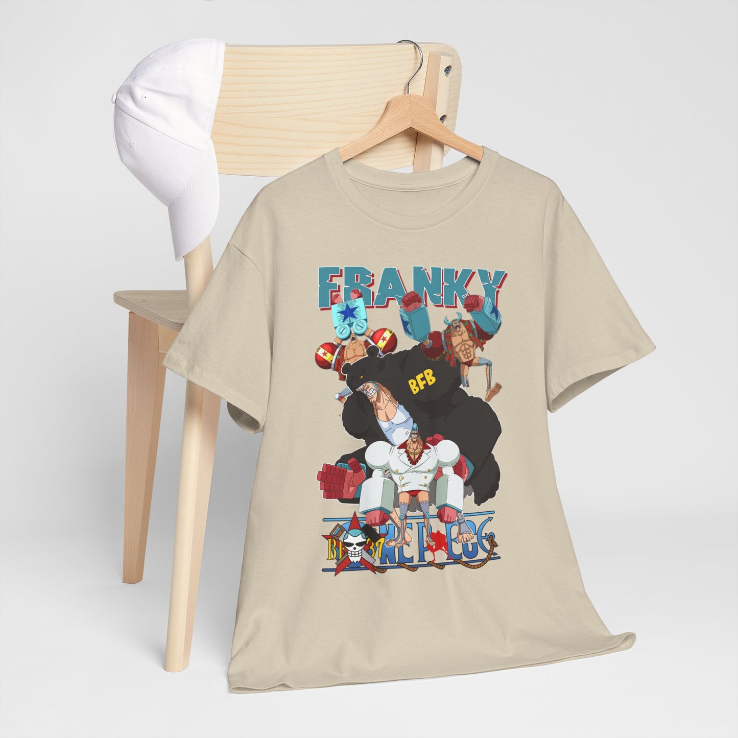 Stylish beige t-shirt adorned with a dynamic Franky anime illustration, displayed elegantly with a white cap on a minimalistic wooden chair.