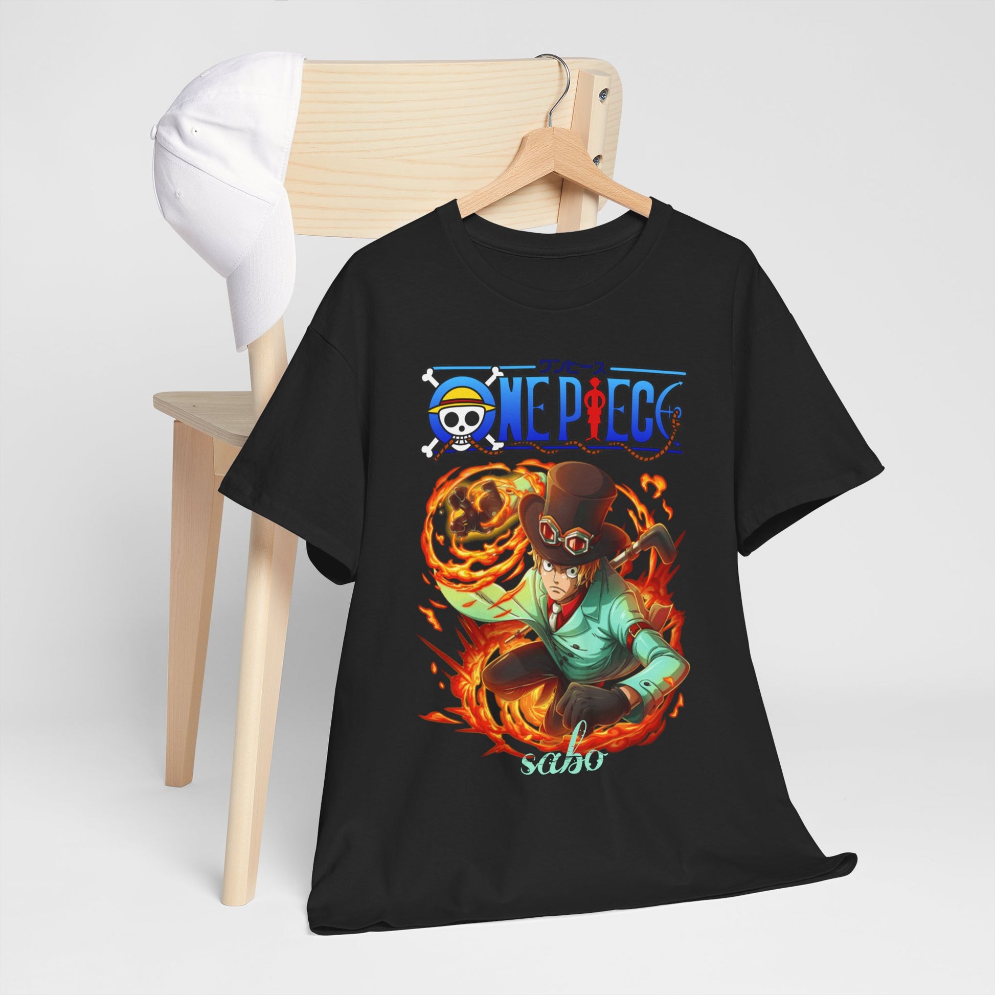 Sophisticated presentation of a black Sabo t-shirt draped over a chair, featuring vibrant One Piece artwork, paired with a white cap for a trendy look.