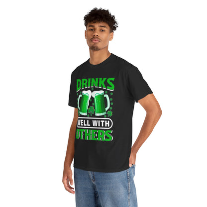 Stylish model wearing a Funny St. Patrick's Day Unisex T-Shirt with 'Drinks Well With Others' and Irish beer mugs, perfect for festive celebrations.