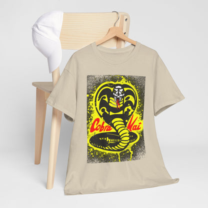 Cobra Kai T-shirt hung alongside a stylish white cap on a wooden chair, showcasing the iconic Cobra design in striking colours against a soft beige hue.