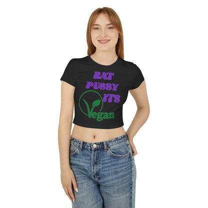 Stylish woman wearing a cropped t-shirt featuring a humorous vegan design with bold typography in purple and green on a black background.