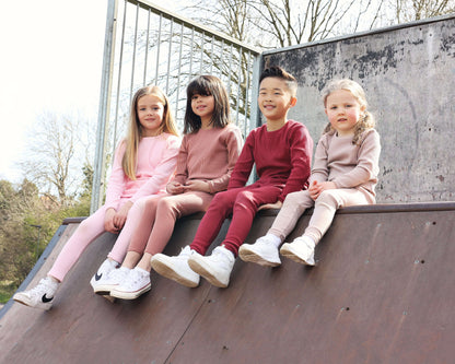 Cozy family lounging in DreamBuy's elegant claret red Christmas pyjamas, ideal for festive play and sleep with a stylish minimalist design.