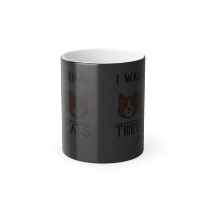 Unique colour-changing "I Was Normal 3 Cats Ago" mug in dark mode, revealing playful cat illustrations, perfect for a luxurious coffee experience.