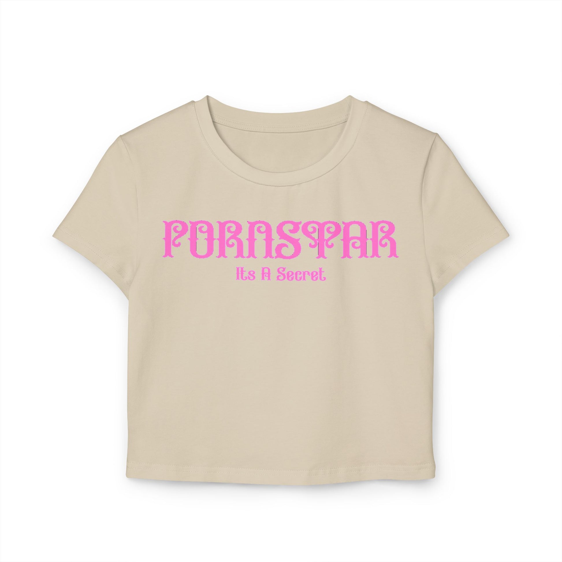 Close-up of the luxurious cropped t-shirt in a soft cream colour, adorned with the cheeky phrase 'Pornstar' and 'It's A Secret' in a stylish pink font, perfect for a fun statement piece.