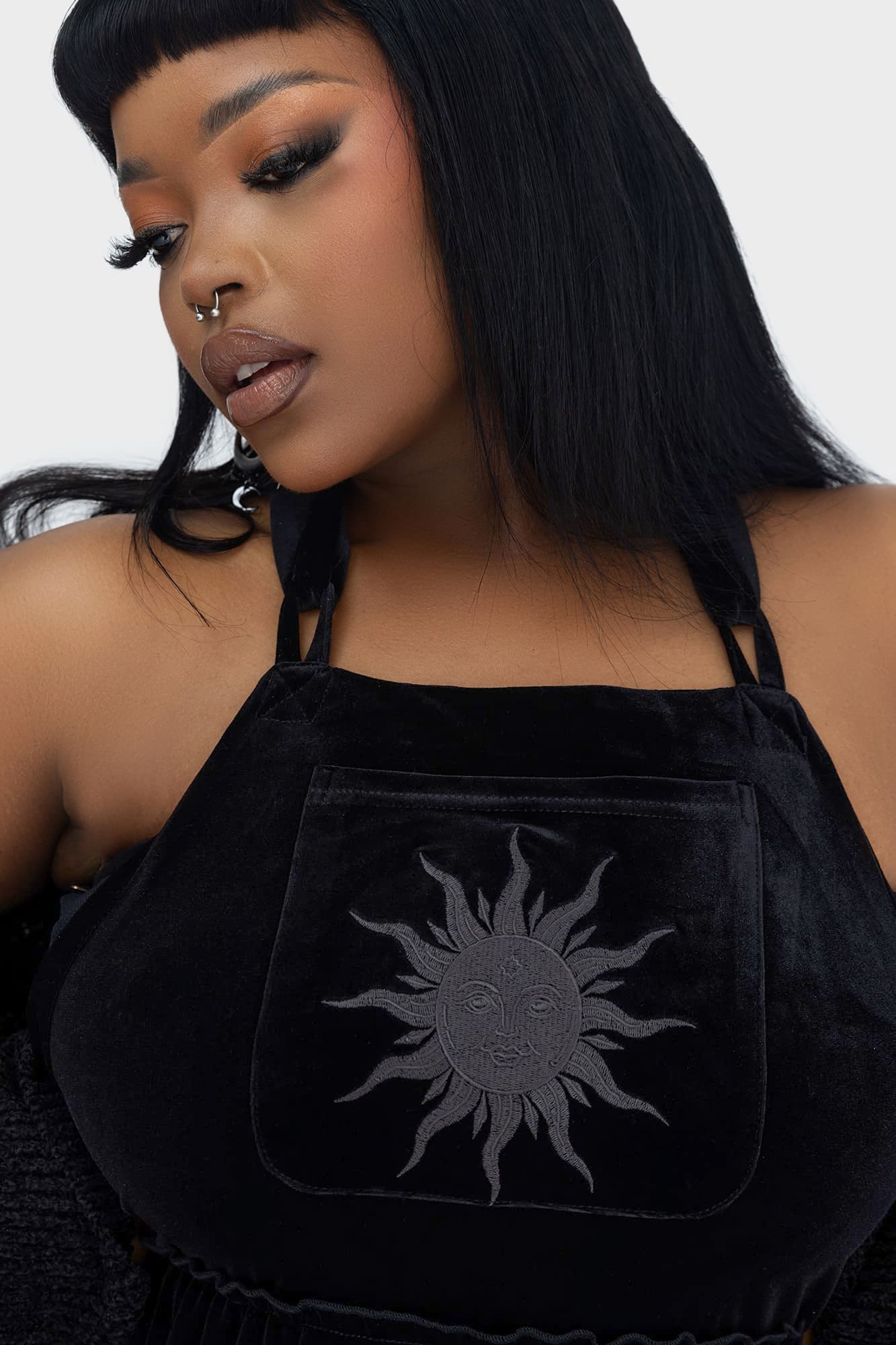Close-up of the bold black sun embroidery on the Killstar Ascended Velvet Maxi Pinafore Dress, enhancing its celestial and edgy appeal.