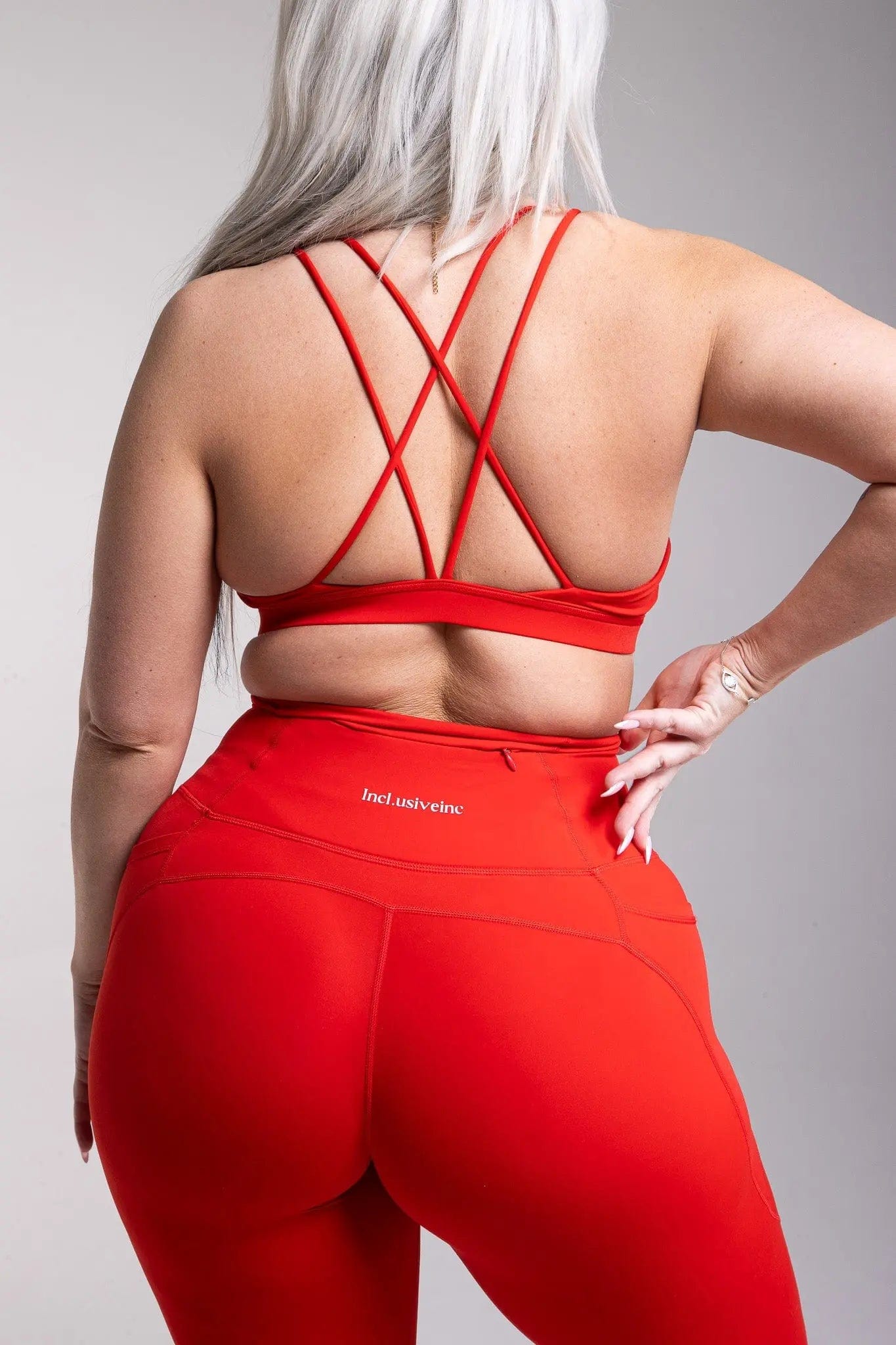 Side view of Incl.usiveinc luxury red leggings in a dynamic pose, emphasizing comfort, style, and utility for active lifestyle.