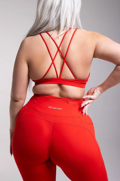 Side view of Incl.usiveinc luxury red leggings in a dynamic pose, emphasizing comfort, style, and utility for active lifestyle.