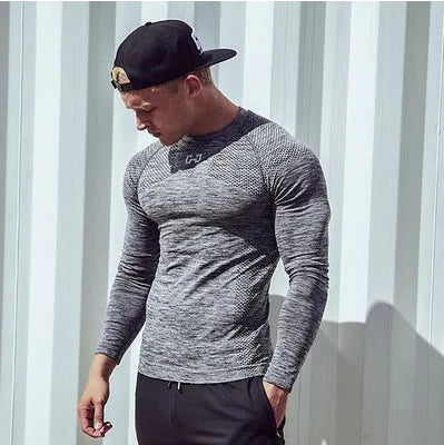 Stylish male model displaying a textured grey compression t-shirt, ideal for sports, set against an urban backdrop, perfect for those seeking fashion in fitness.