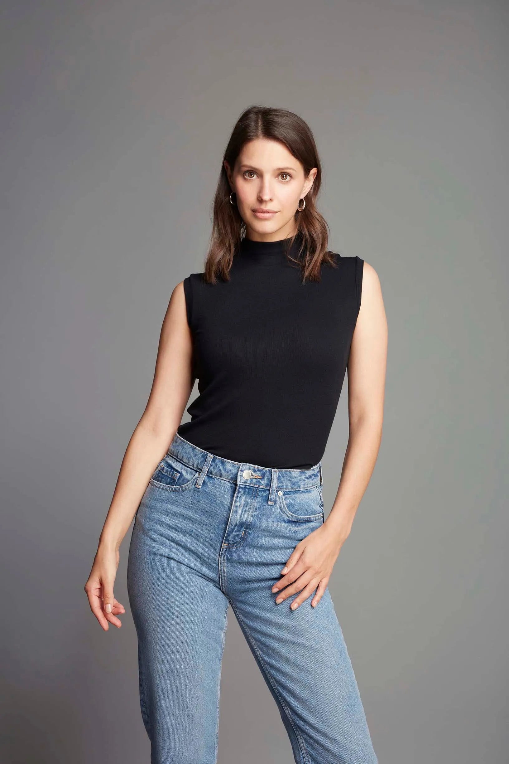 Fashionable model wearing a luxury sleeveless mock neck top paired with tailored trousers, exemplifying effortless style for both casual and formal settings.