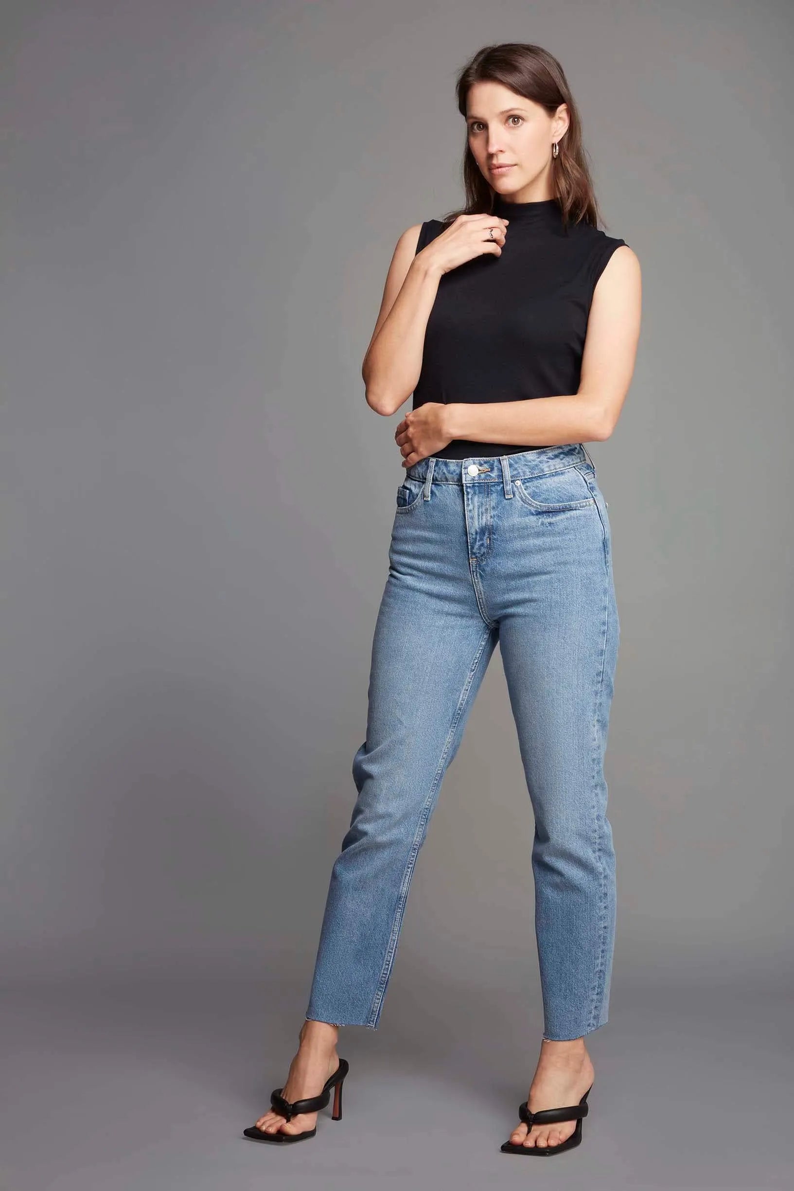 Fashionable model wearing luxury sleeveless mock neck top in ribbed Micro Modal, styled for a casual yet elegant look, available in sizes 8-16.