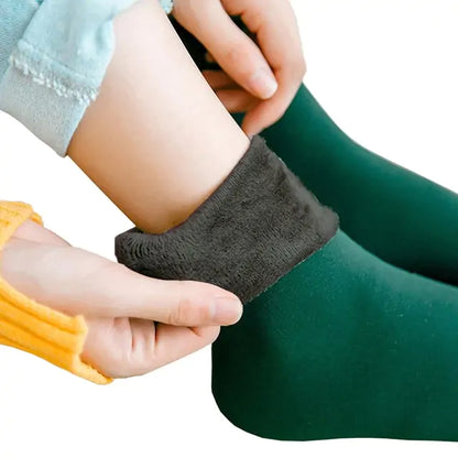 Luxury Women's Velvet Thermal Socks: Close-up of hands putting on soft, green thermal socks, showcasing the plush velvet top.