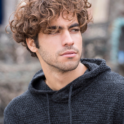 Model wearing the Iguazu Recycled Knitted Hoodie in a natural setting, exemplifying sustainable luxury in fashion.