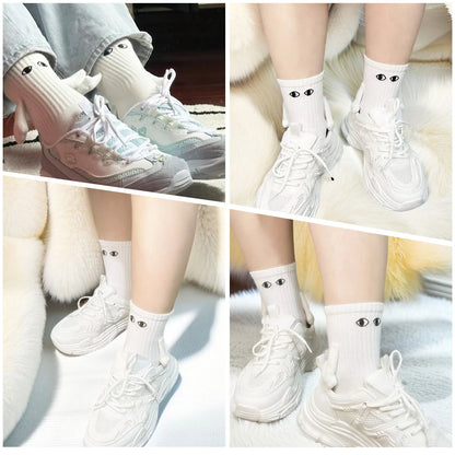 Novelty Romantic Magnetic Holding Hands Couple Socks displayed on a model's feet, featuring a playful design with eyes, paired with casual sneakers.