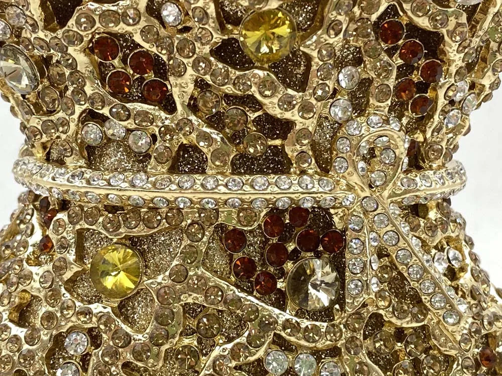 Stunning minaudiere handbag showcasing a metallic finish and sophisticated floral cut-out pattern, ideal for glamorous evening events.