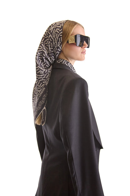 Stylish display of the Helen Anthony silk scarf draped, showcasing its graceful drape and stunning monogram print, a perfect accessory for sophisticated attire.