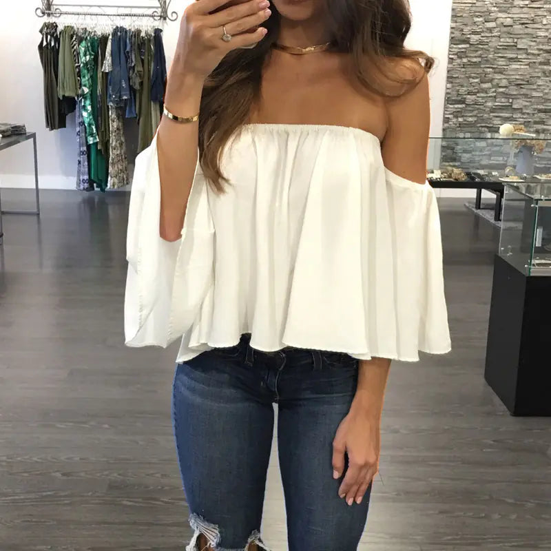 Stylish white chiffon blouse with flared sleeves, accentuating an off-shoulder look, captured in a trendy boutique setting.