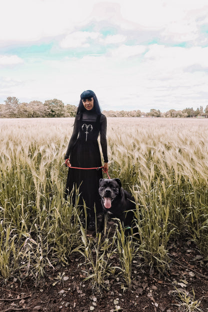 Full view of a model wearing the Dark In Love Lux Black Velvet Maxi Dress showcasing its flowing silhouette and gothic elegance at a fashionable event.