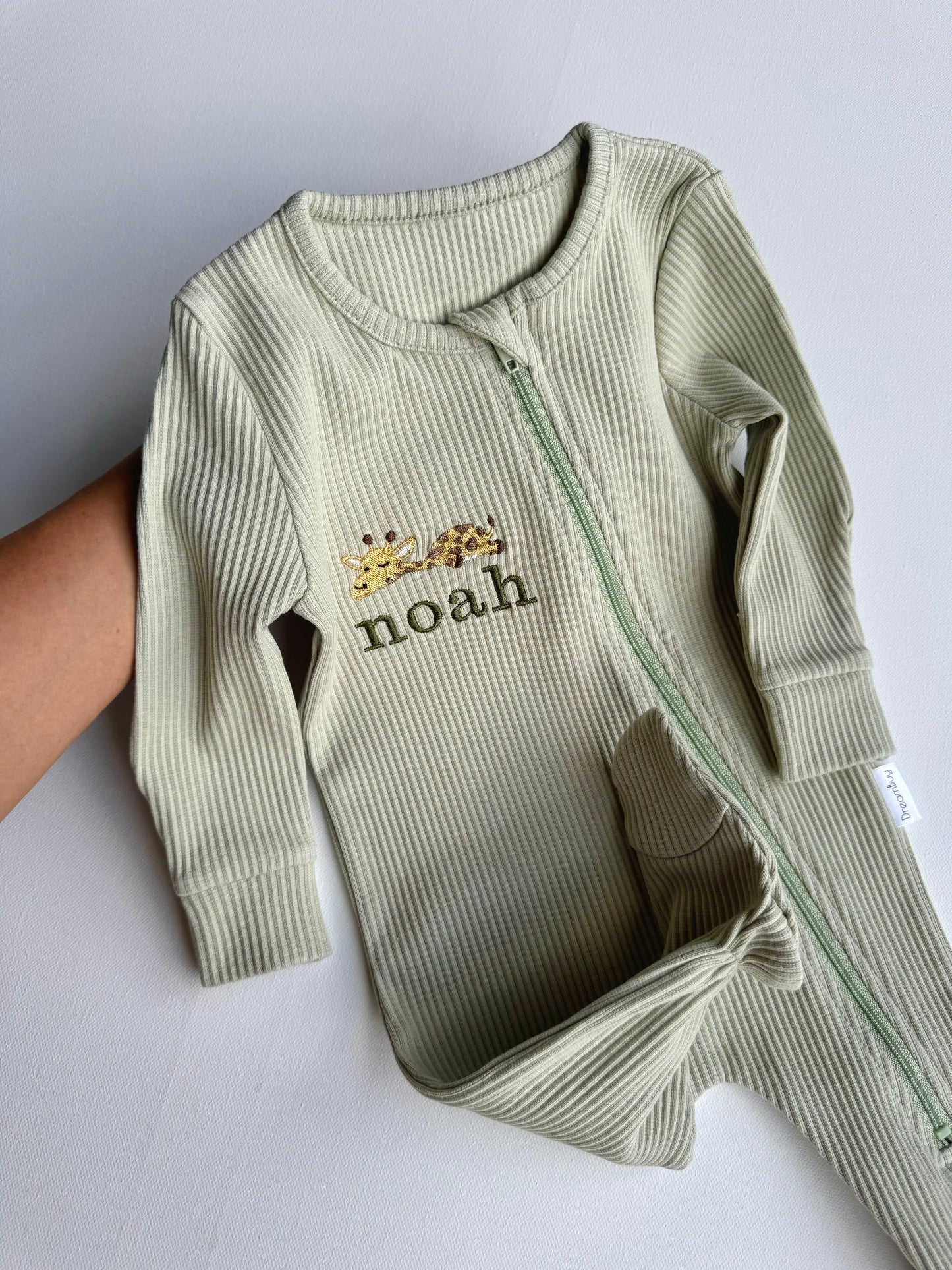 Luxury personalised safari-themed baby zip romper from DreamBuy featuring vibrant animal embroidery including a lion, unicorn, sheep, giraffe, and cow, crafted from high-quality soft ribbed cotton for ultimate comfort.