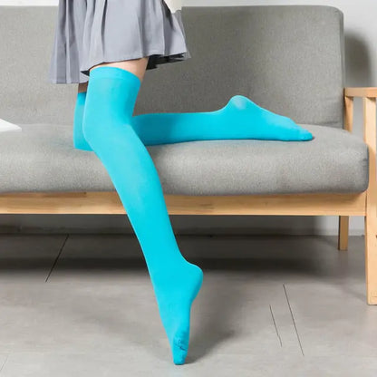 Chic Women's Black White Solid Color Long Socks Stockings in a striking turquoise colour paired with a fashionable grey skirt on a sleek sofa.