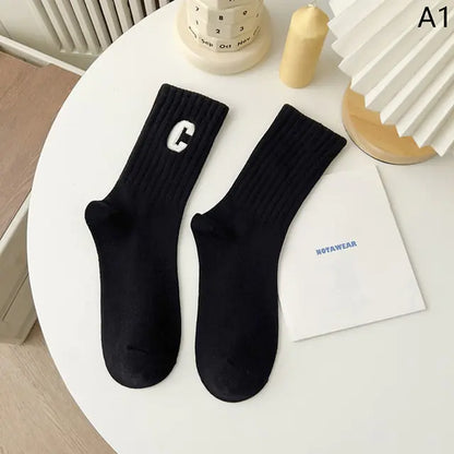 Sophisticated Women's Tie-Dye Middle Tube Socks in deep black, featuring a contrasting white letter 'C' on the ribbed top, combining chic style and all-day comfort.