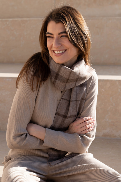 Stylishly wrapped luxury undyed alpaca plaid scarf displayed against a serene winter backdrop, perfect for chilly days.