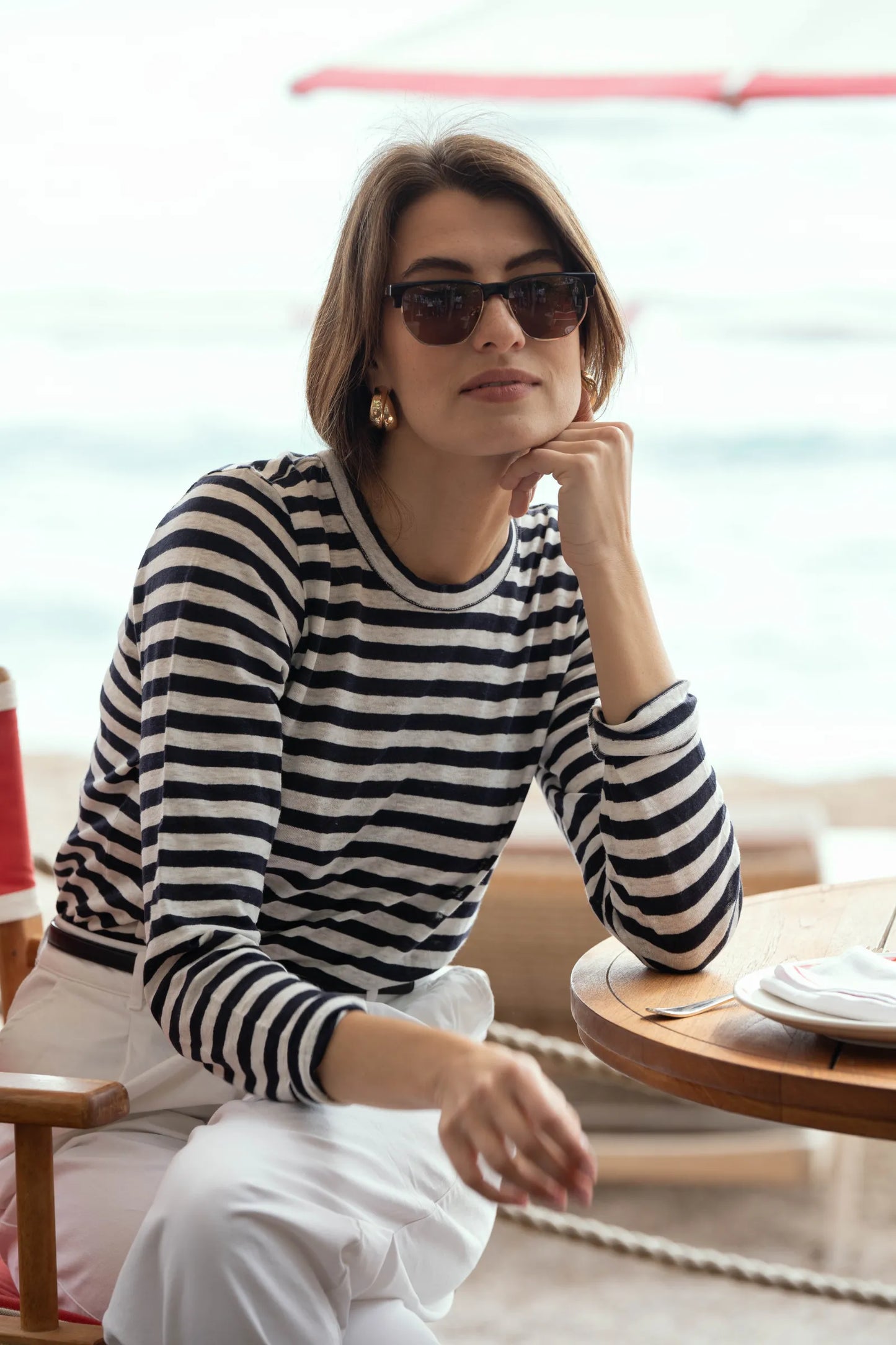 Lifestyle imagery of women wearing striped linen t-shirt, demonstrating relaxed fit and timeless elegance in vibrant outdoor setting.