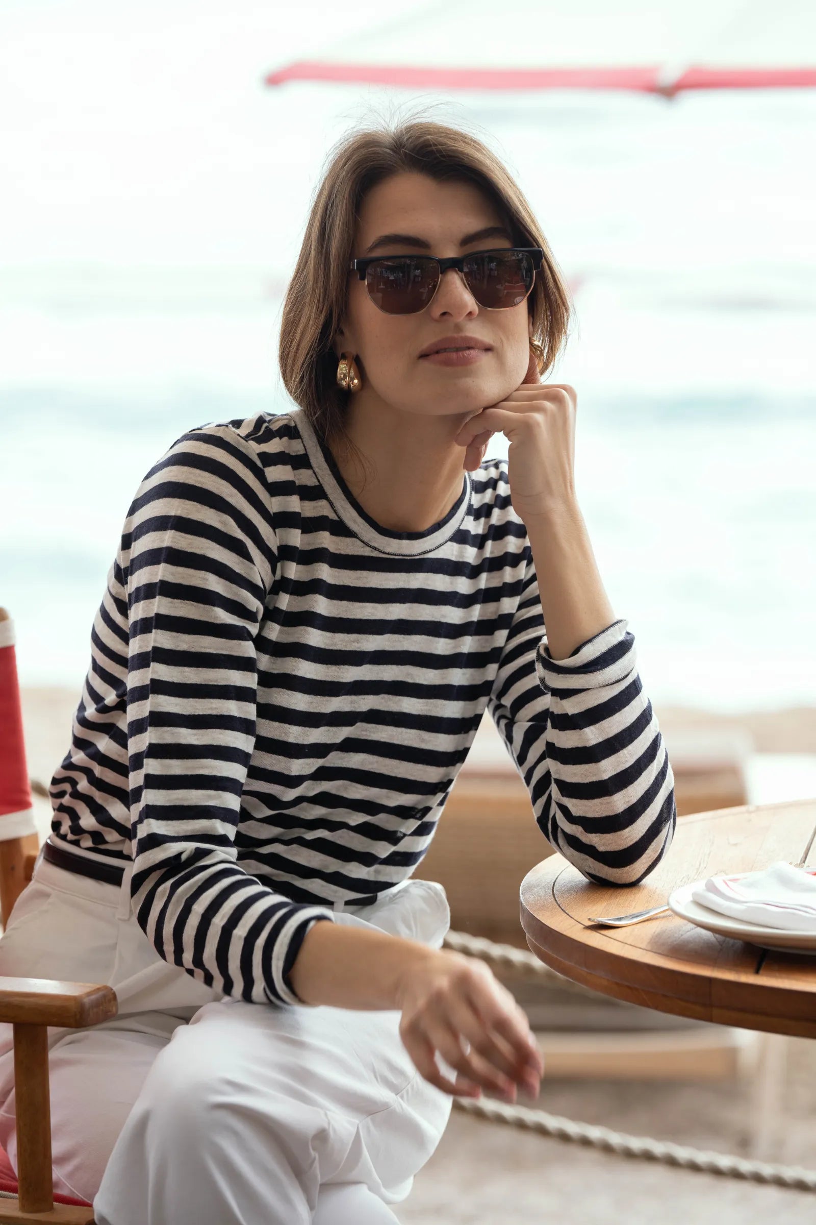 Lifestyle imagery of women wearing striped linen t-shirt, demonstrating relaxed fit and timeless elegance in vibrant outdoor setting.
