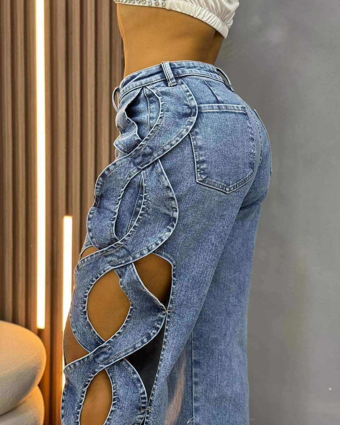 Close-up view of BKQU elegant blue denim jeans, featuring delicate hollow out embellishments that elevate casual attire to chic elegance.
