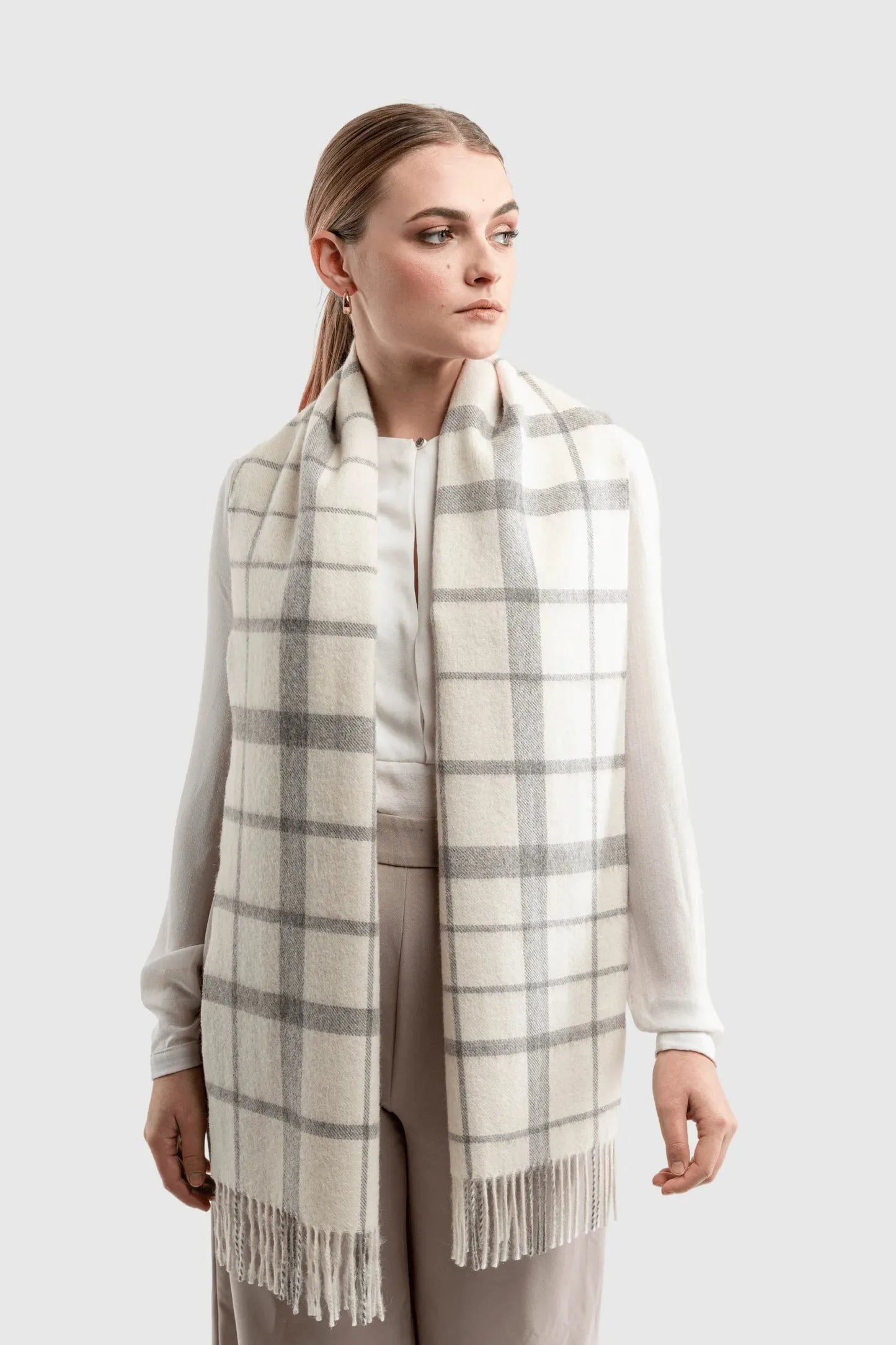 Beautifully styled undyed alpaca plaid scarf with twisted fringes, featuring natural colours and ideal for a chic winter look.