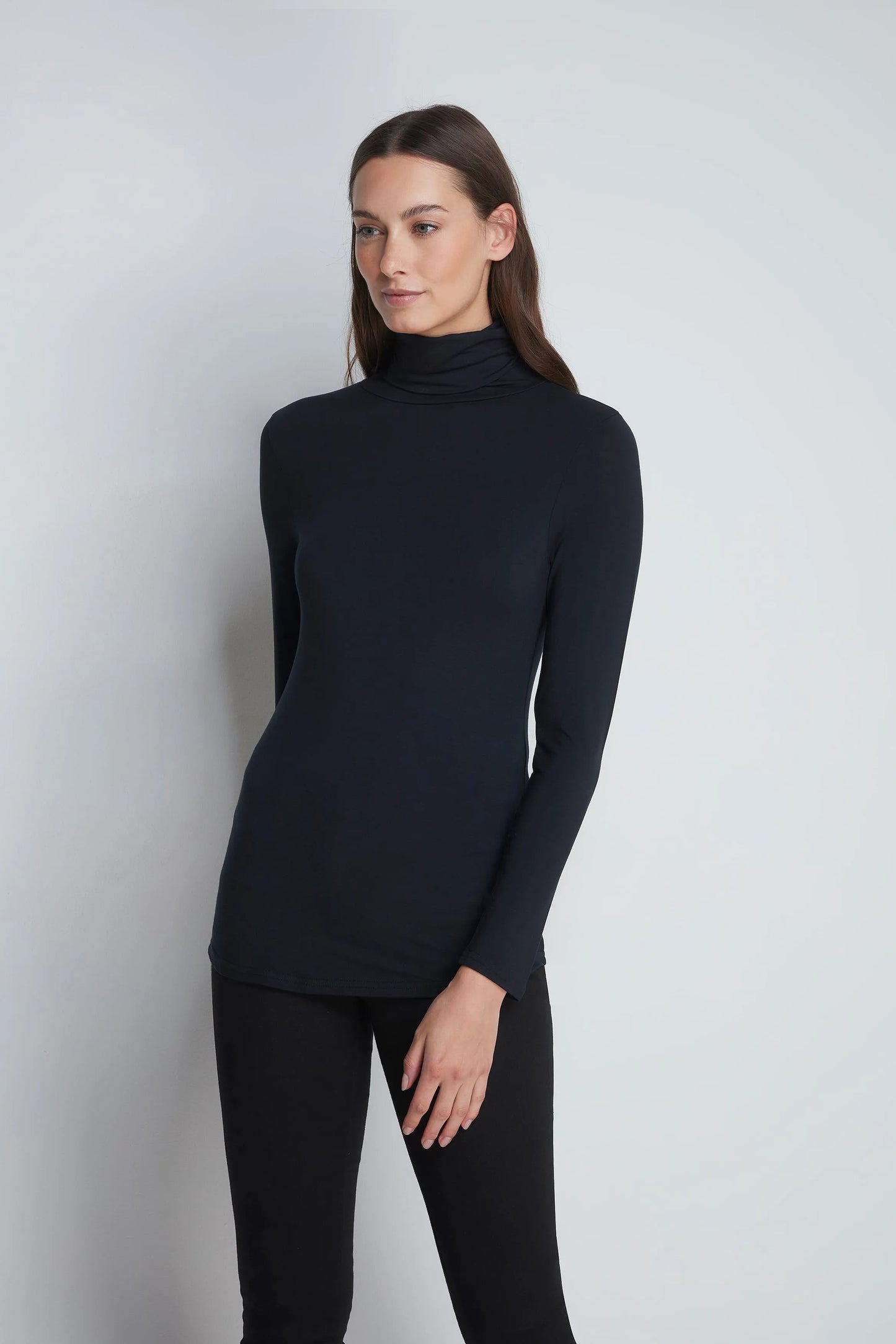 Model wearing Women’s roll neck TENCEL™ Micro Modal Top styled with tailored trousers, illustrating versatility for an elegant office attire.