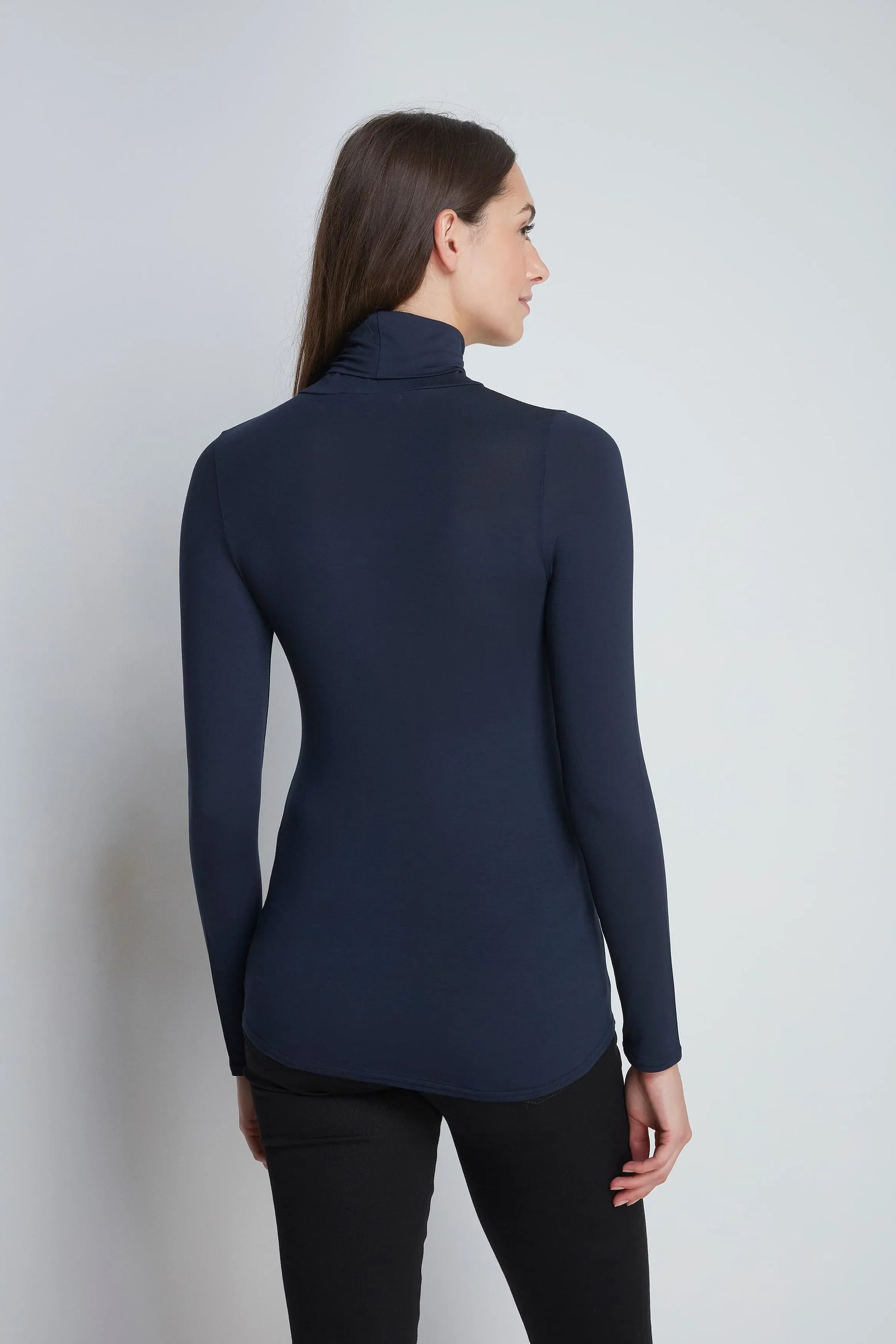 Model wearing Women's Roll Neck TENCEL™ Micro Modal Top, styled with tailored trousers, illustrating versatile elegance for both office and casual wear.