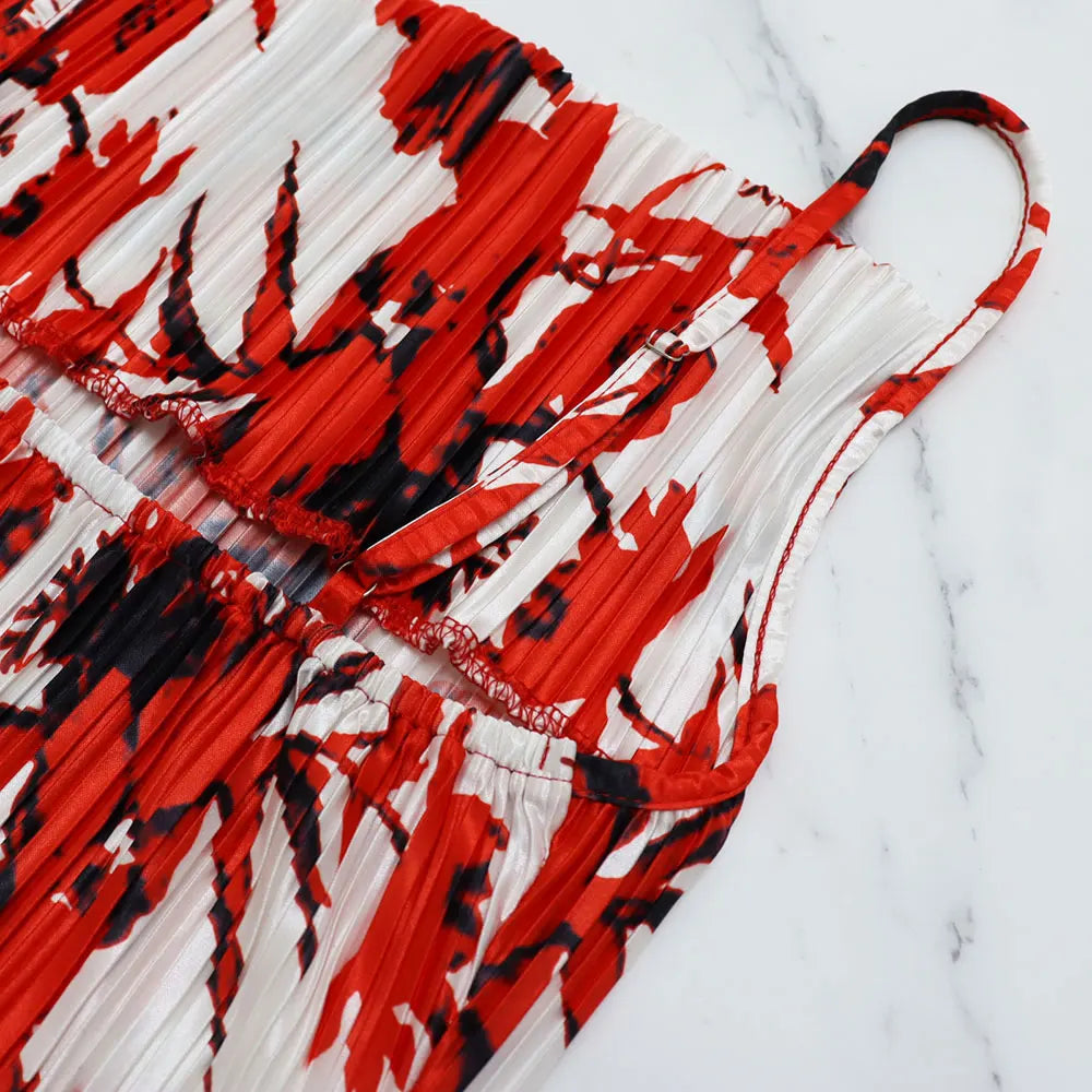 Luxury women's summer dress paired with sandals on a beach, highlighting the elegant spaghetti strap design and pleated detail.