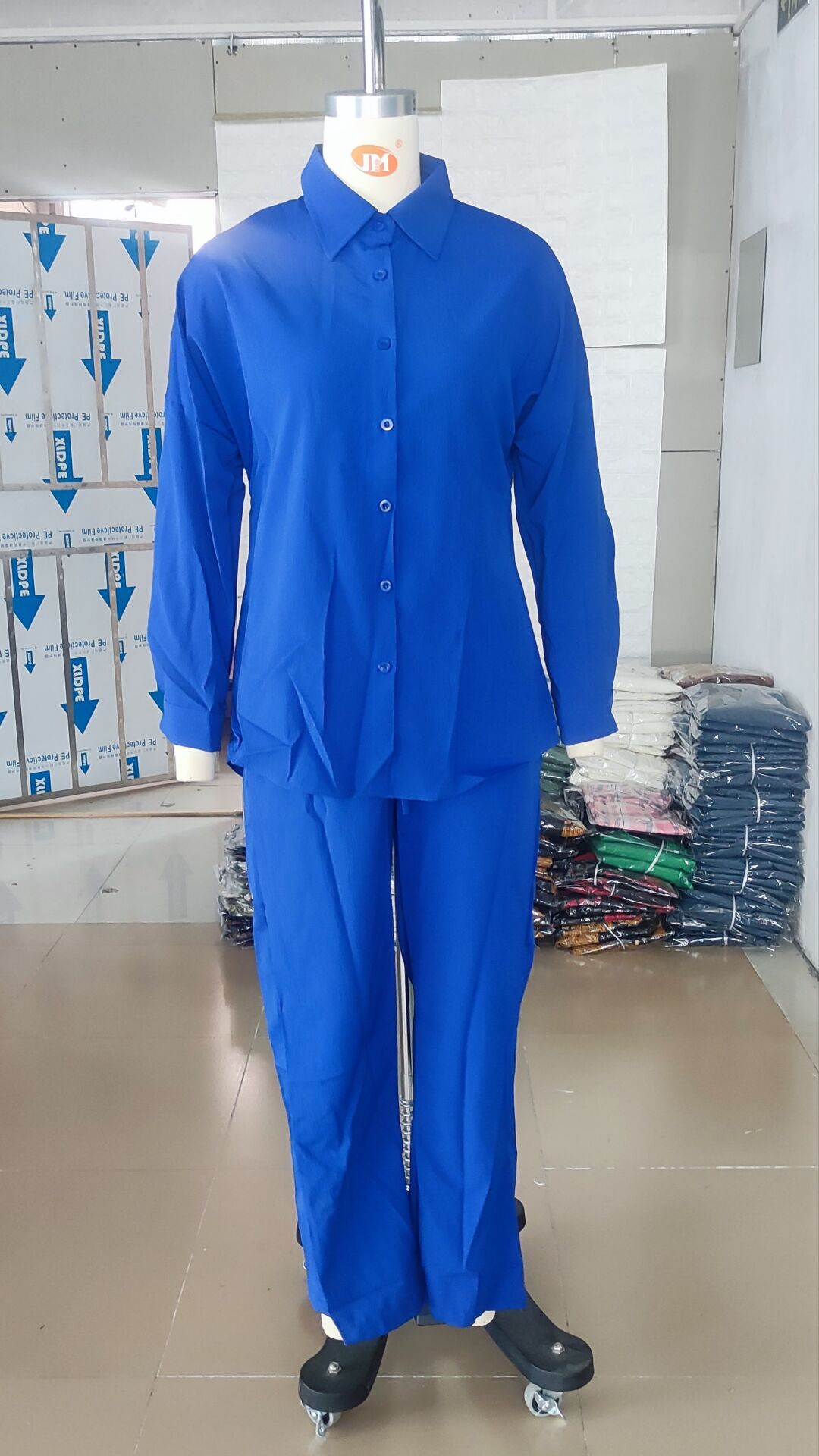 Close-up detail of the polo-neck and pleated front style on a luxury women's shirt.