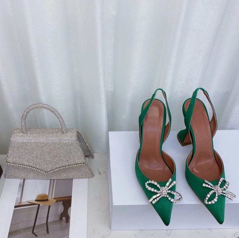 Close-up of luxury women's pointed toe sandals adorned with rhinestone bows, showcasing exquisite craftsmanship and stylish metal decorations.