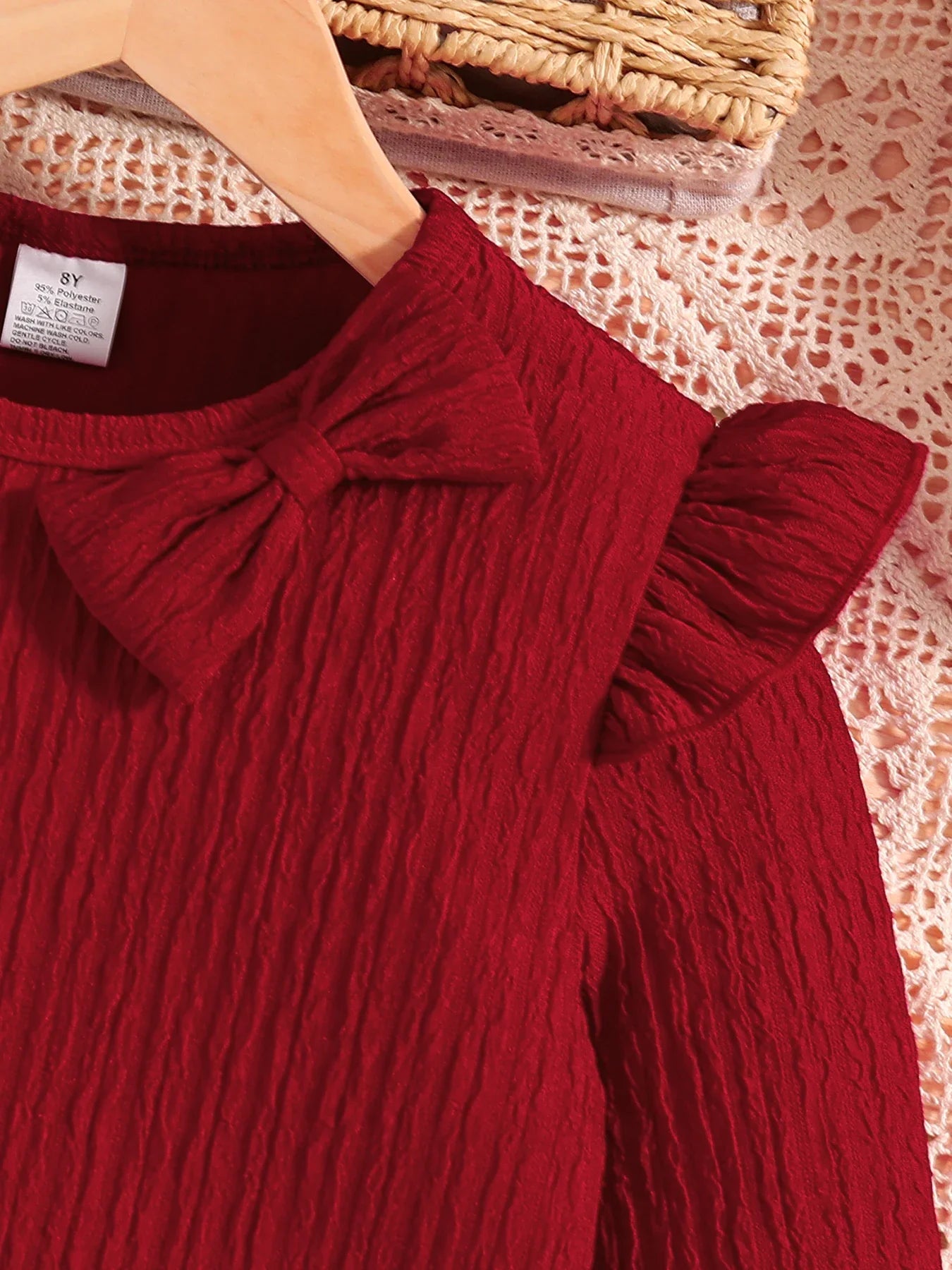 Stylish girl wearing a luxury autumn red dress made of soft knitted fabric, ideal for vacation looks and casual outings, featuring an eye-catching bow.